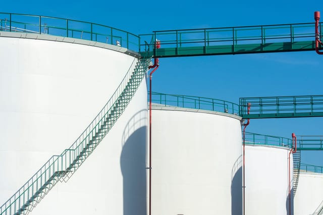 Above ground storage tanks with access walkways and stairways against a clear sky
