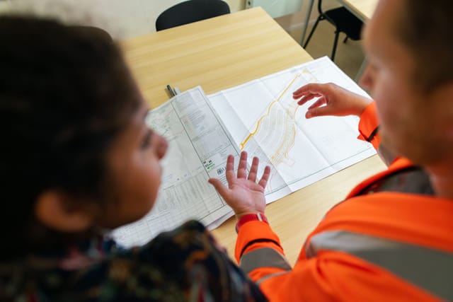 Two engineers in hi-vis reviewing a site plan across a table