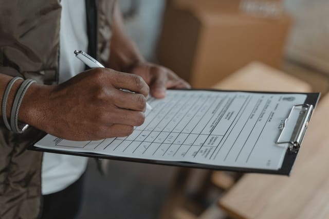 Inspector completing a compliance form on a clipboard with a pen