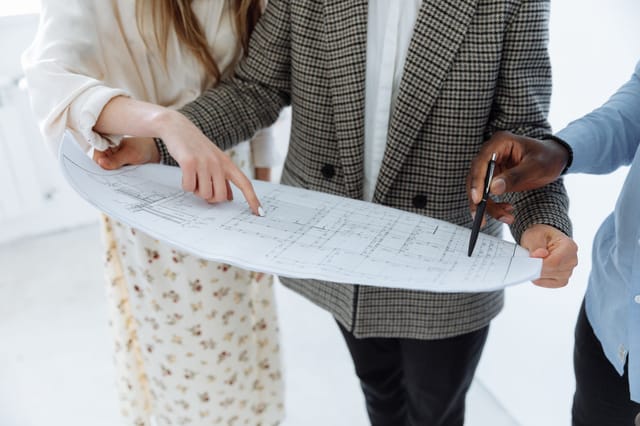 Two people reviewing a technical drawing with a pen while planning a repair