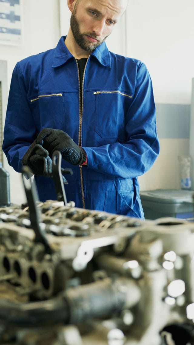 Gloved hands handling metal components during material checks
