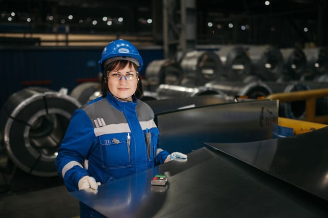 Worker inspecting metal sheet material in an industrial plant