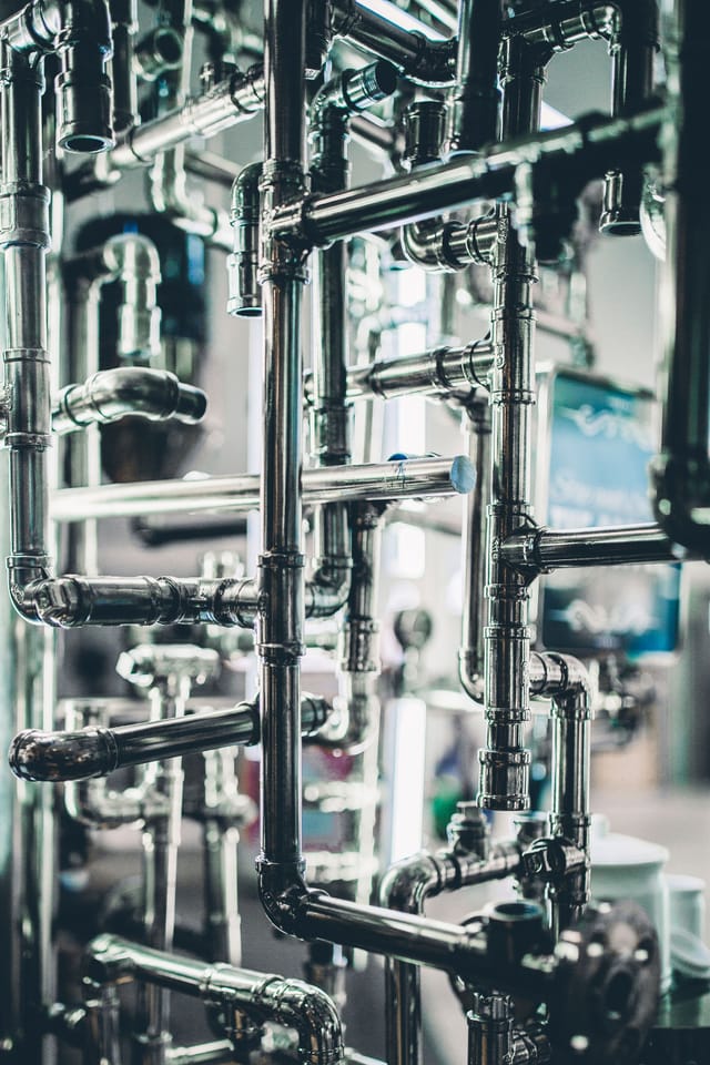 Dense stainless process pipework with flanges and fittings inside an industrial plant