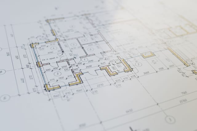 Dimensioned plant layout drawing with a scale ruler on a desk