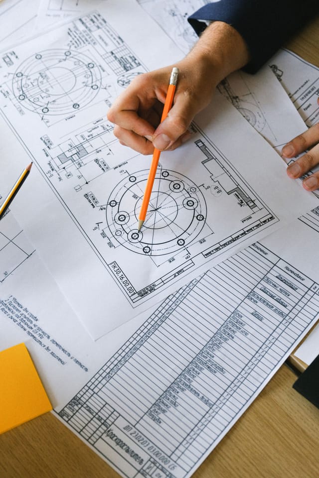 Engineer checking a dimensioned pipework detail drawing with a title block on the desk