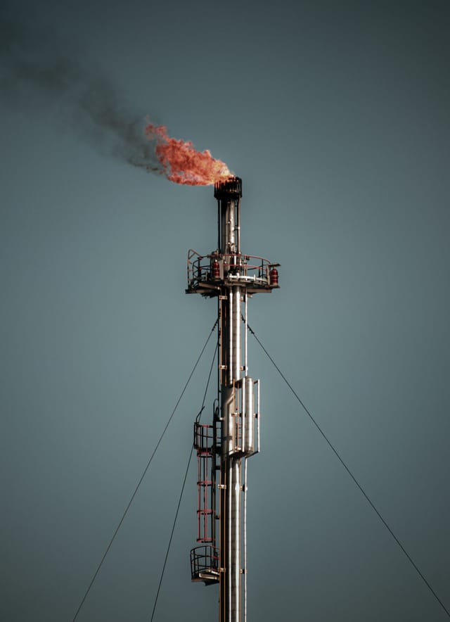 Flare stack burning against the sky with access platforms and ladders at height