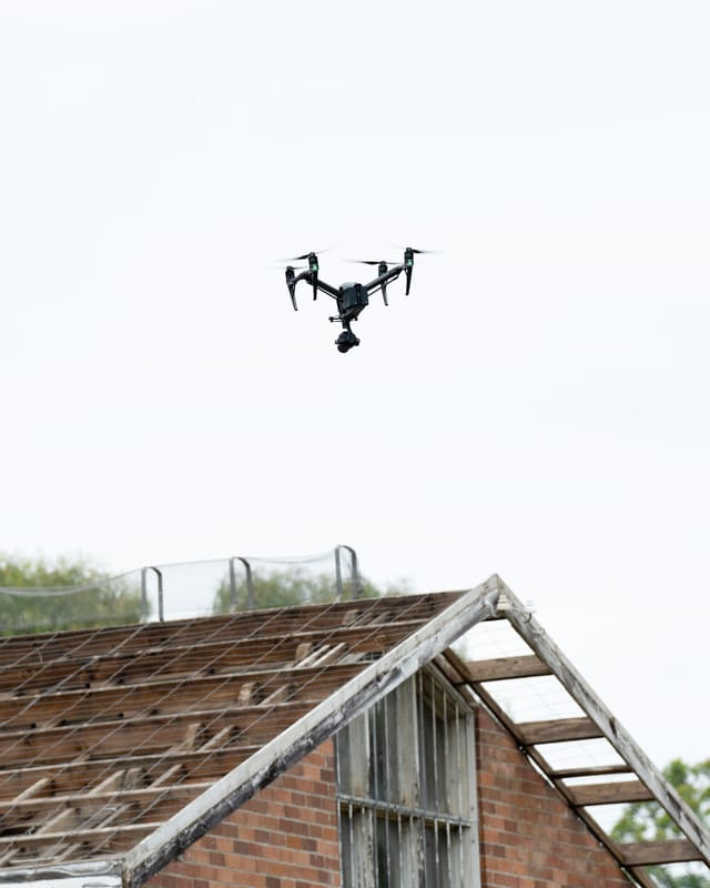 Inspection drone with a camera gimbal flying above an industrial structure against a clear sky