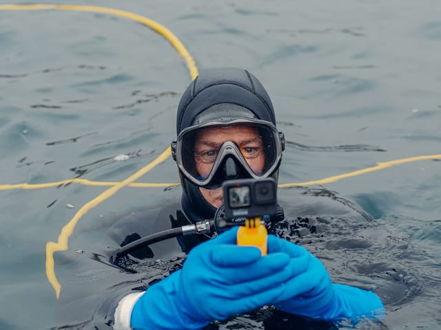 Operator at the surface preparing a tethered inspection camera on a yellow umbilical