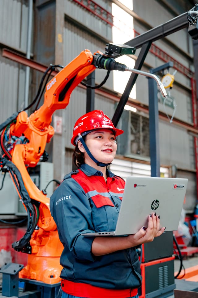 Technician in hard hat reviewing inspection data on a laptop beside inspection equipment