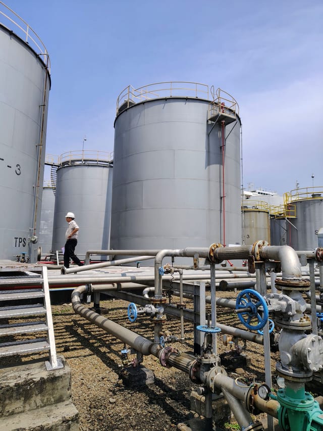 Inspector walking between above ground storage tanks and pipework at an industrial site