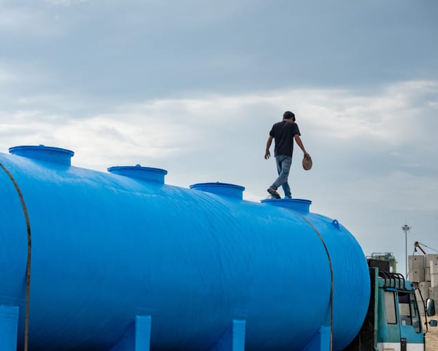 Large blue plastic storage tank with a worker walking across the top