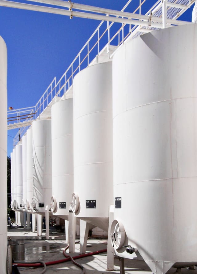 A bank of new white cylindrical storage tanks against a pale sky
