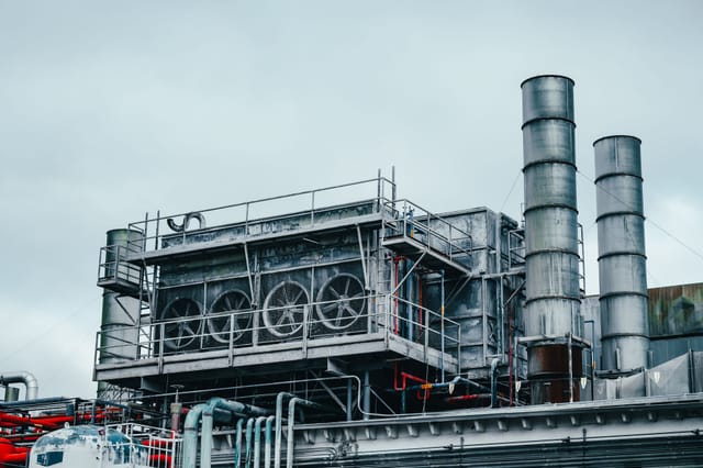Industrial process plant module with pipework, coolers and vent stacks against a grey sky